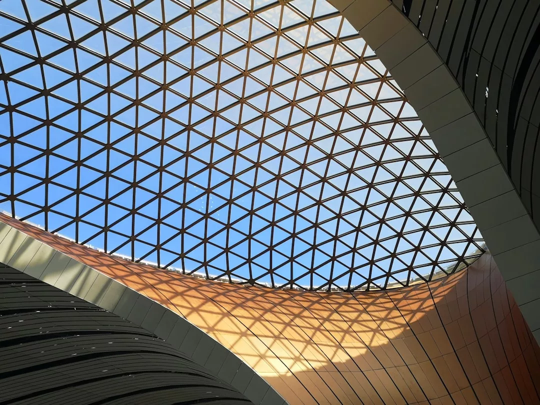 Geometric glass ceiling with a grid pattern allows sunlight to illuminate the curved interior structure below, creating a modern ambiance that appeals to evolving buyer preferences in the Cologne real estate market.
