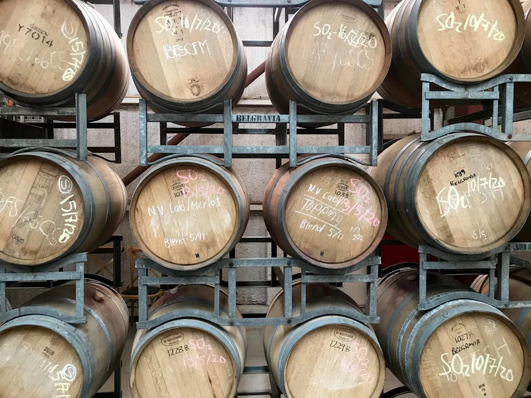 Stacked wooden barrels with handwritten chalk markings on their heads, arranged in a metal rack within a storage or winery setting—highlighting unique features ideal for wine-focused real estate opportunities.