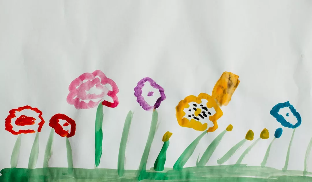 Child’s drawing of colorful flowers with green stems and leaves on white paper, featuring red, pink, purple, yellow, and blue blossoms—a cheerful touch perfect for brightening any real estate listing or staging a welcoming space.