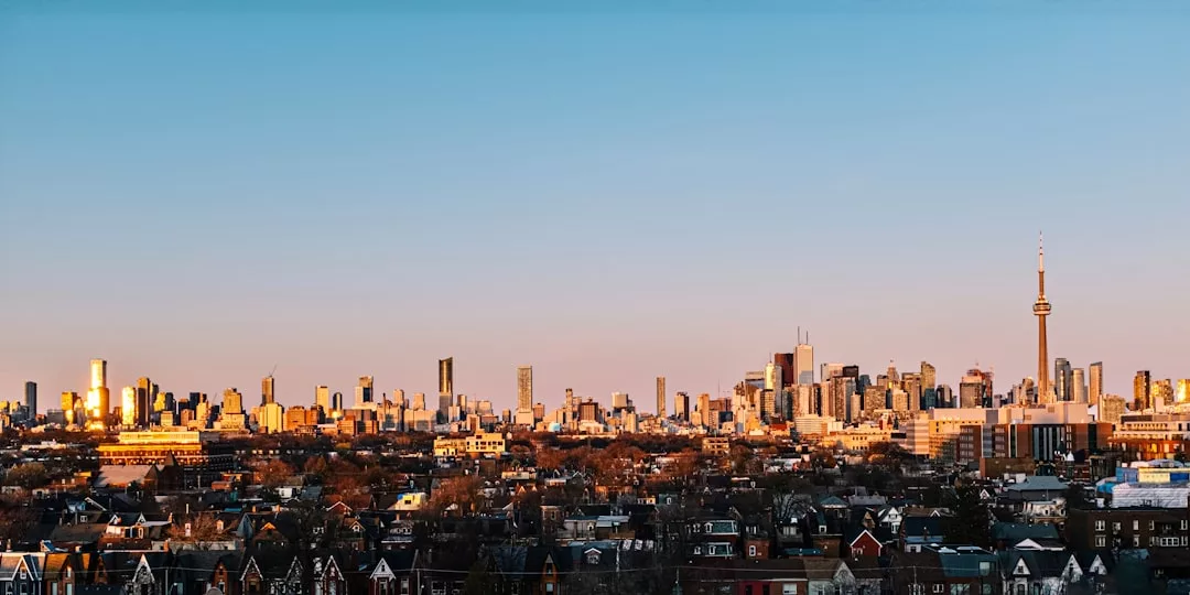 Toronto skyline at sunset, featuring the CN Tower and high-rise buildings above residential neighborhoods under a clear sky, exuding urban luxury reminiscent of Södermalm in Stockholm.