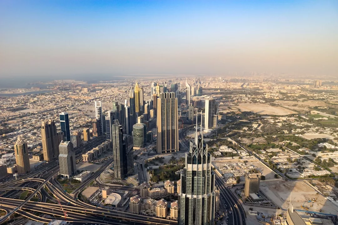 Aerial view of a modern city skyline with tall skyscrapers, highways, and vibrant urban landscape—an ideal setting for prime real estate opportunities under a clear sky.