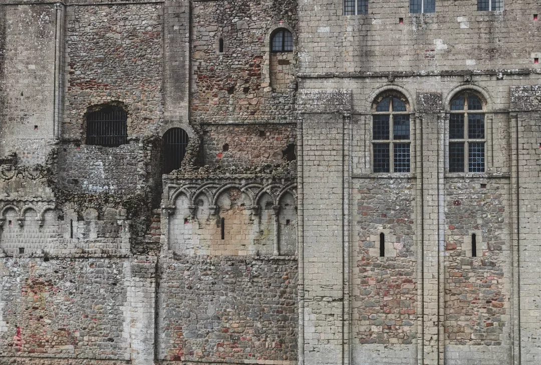Close-up of an old stone building facade with arched windows, decorative stonework, and weathered walls showing signs of age—a distinctive feature for unique real estate opportunities.