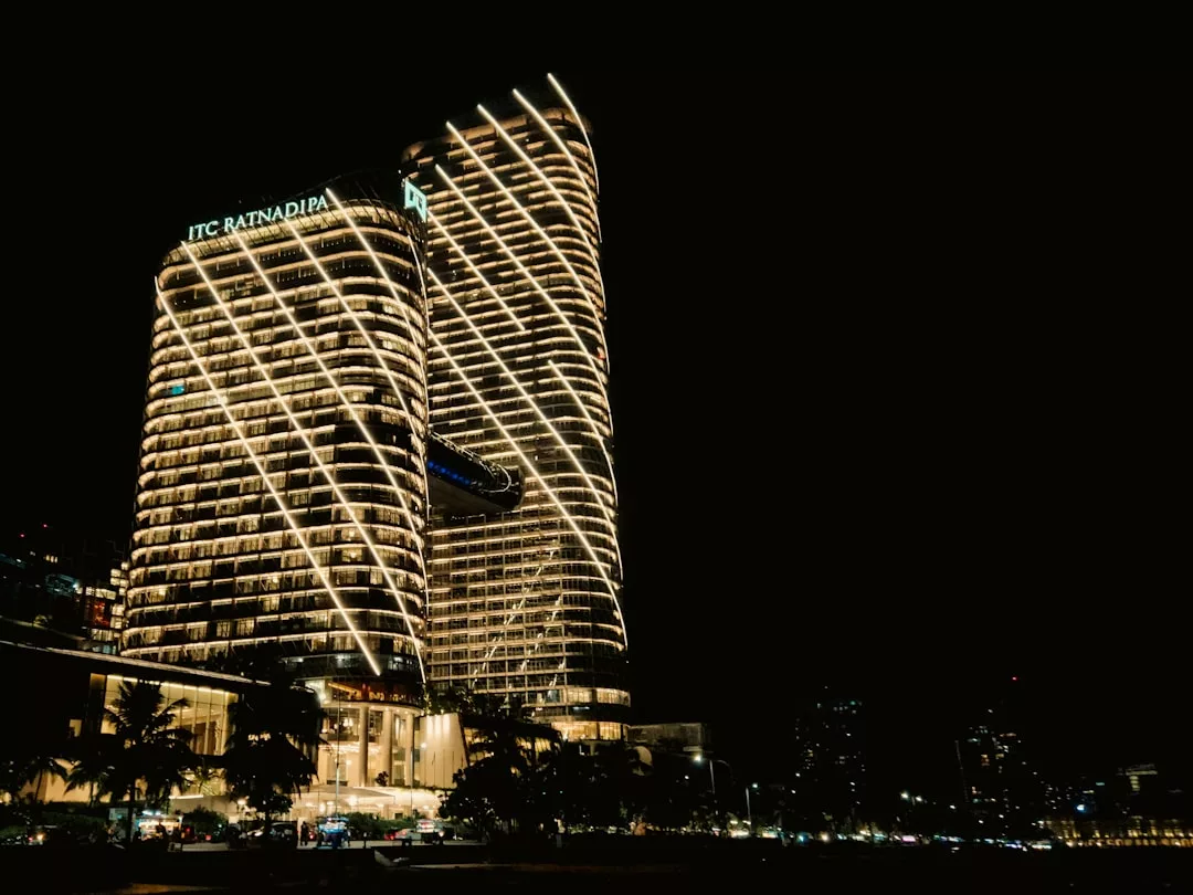 Two modern high-rise buildings, labeled ITC Ratnadipa, shine with bright lines of lights against a dark night sky—an impressive landmark in real estate.