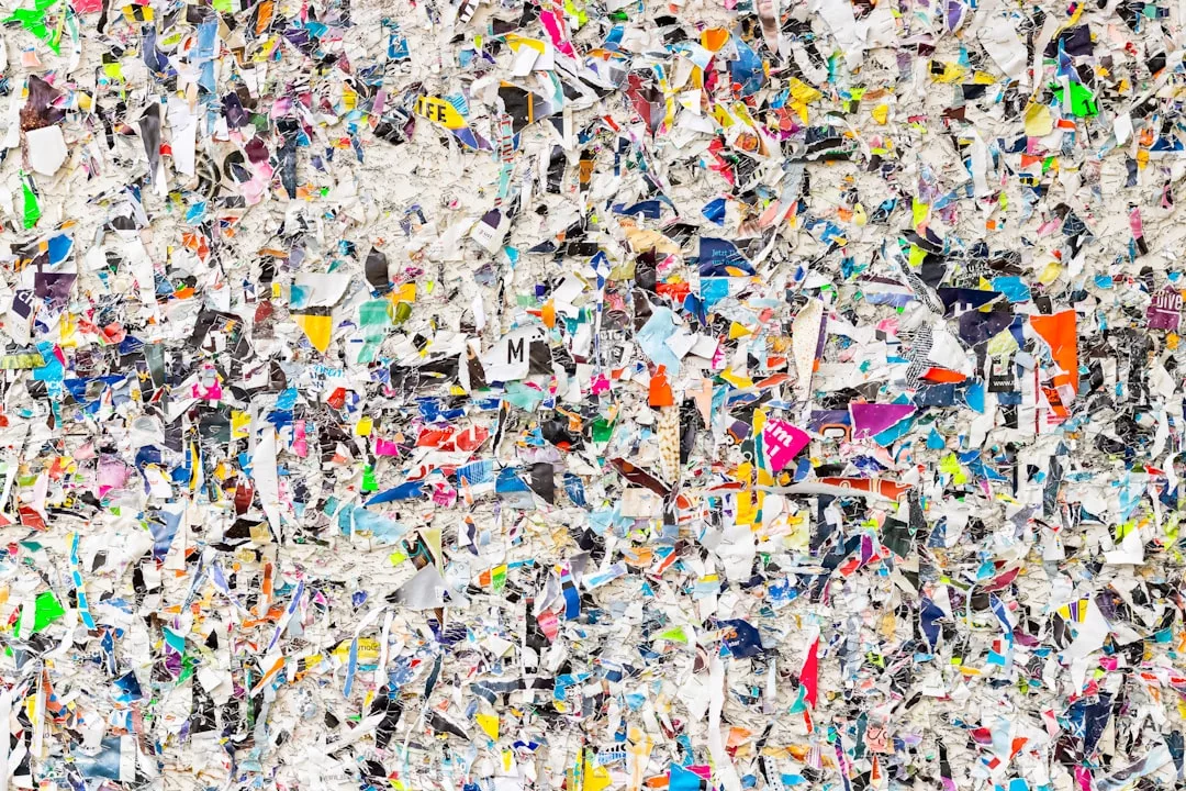 A densely packed pile of shredded, multicolored paper pieces fills the entire frame, creating a chaotic and textured surface reminiscent of real estate documents freshly processed in an office.
