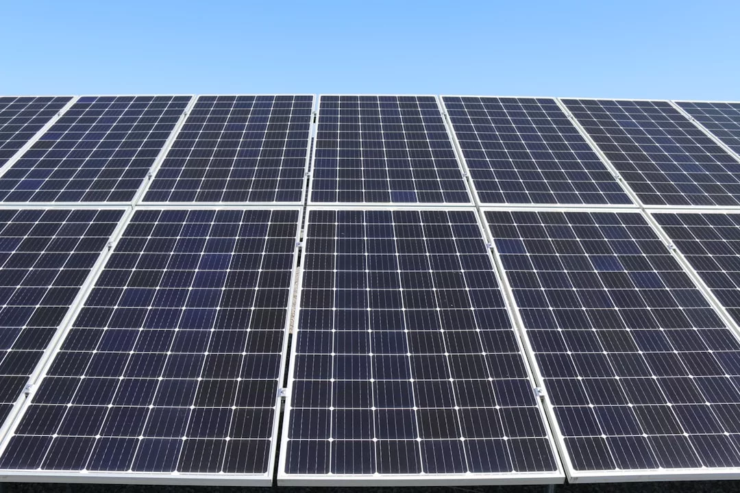 Rows of dark solar panels are arranged in a grid pattern under a clear blue sky, generating renewable energy from sunlight—a sustainable feature increasingly valued in modern real estate.