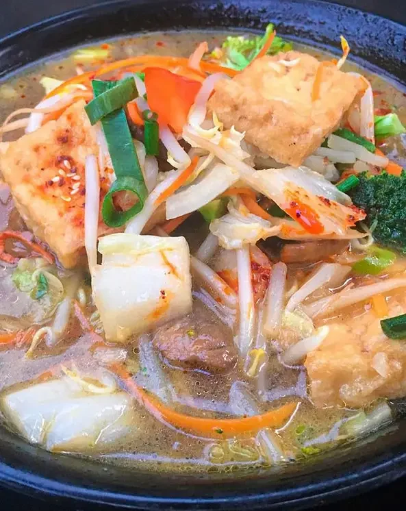 Clear soup with fish and vegetables in a dark bowl