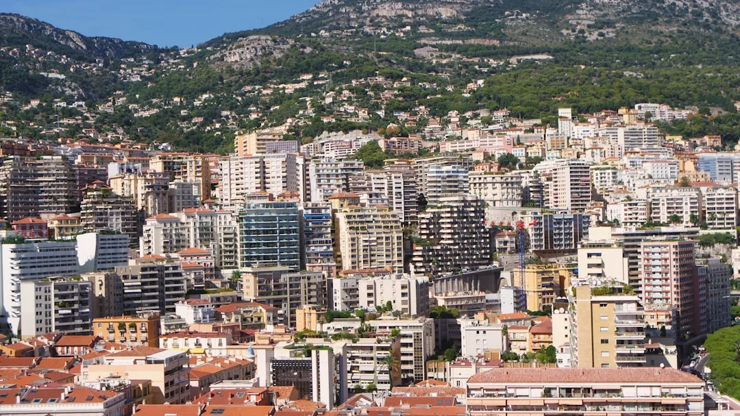 A densely packed cityscape with many mid- and high-rise apartment buildings, set against a hillside covered with greenery—a vibrant real estate hub blending urban living with natural beauty.