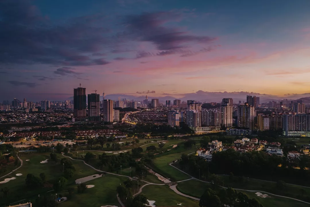A city skyline at sunset with high-rise buildings and a golf course in the foreground, showcasing prime real estate opportunities.