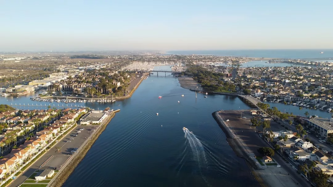 Aerial view of a coastal city with boats on a canal, bridges, residential areas, marinas, and prime real estate opportunities under a clear sky.