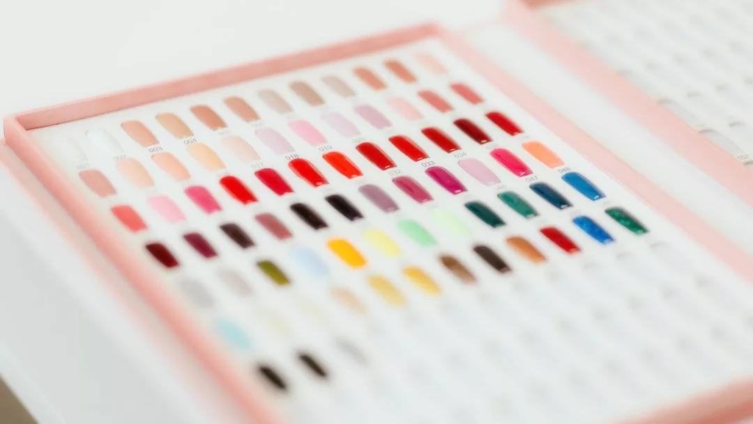 Display case with rows of artificial nail samples in various colors and finishes, arranged neatly inside a pink-edged box—perfect for adding a touch of style to your real estate office decor.