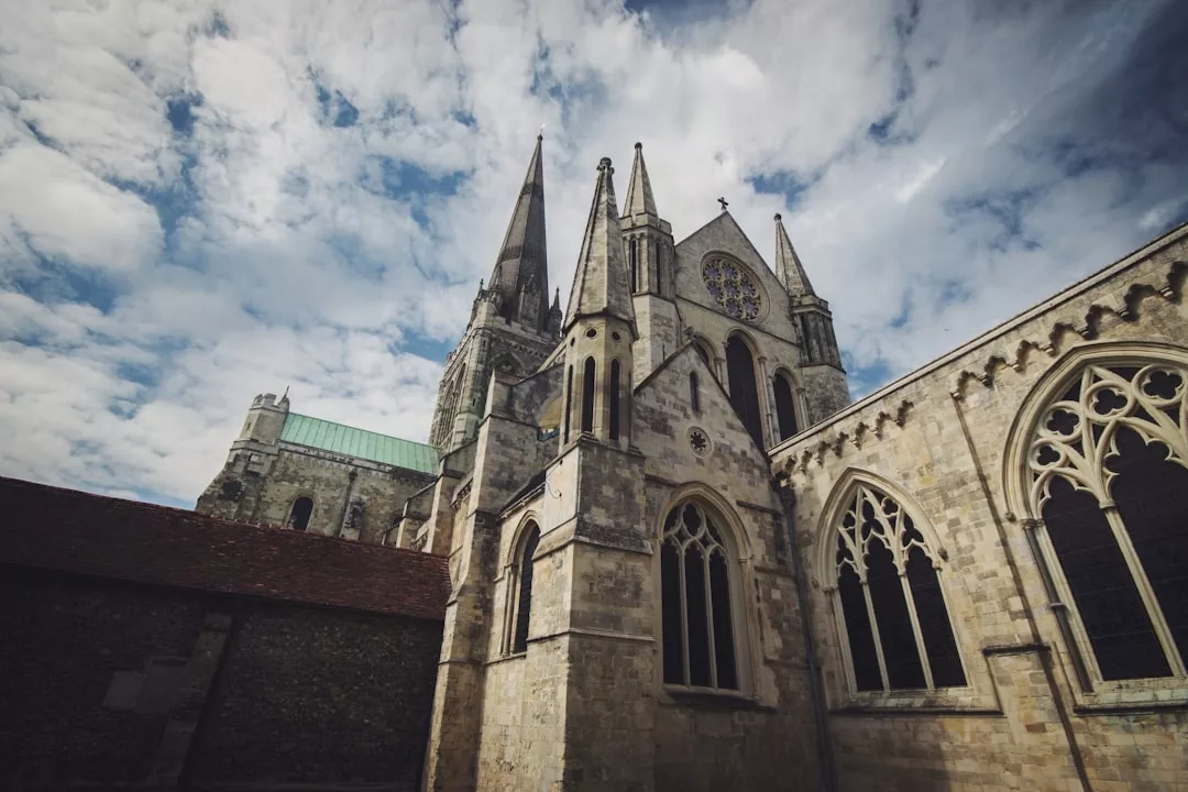 A large Gothic cathedral with pointed arches and tall spires stands beneath a partly cloudy sky, offering impressive real estate inspiration for those who admire historic architecture.