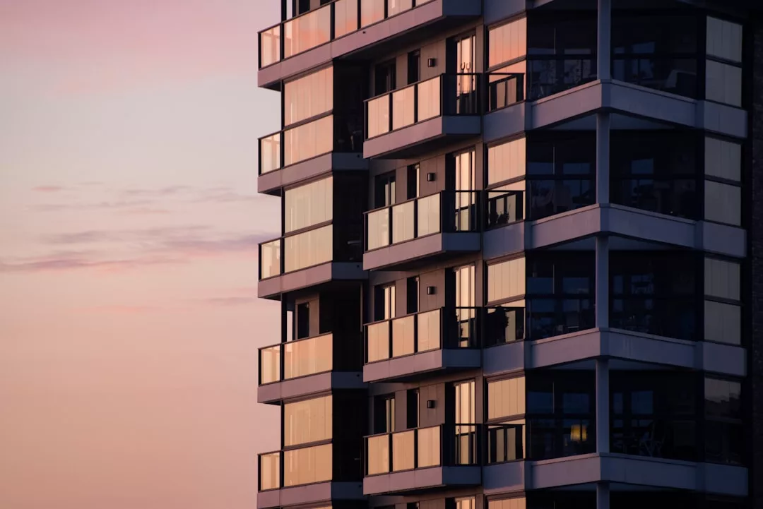 Modern apartment building with glass balconies in Copenhagen, photographed at sunset with warm light reflecting off the windows—a standout for real estate agencies and anyone seeking a buyers guide to city living.