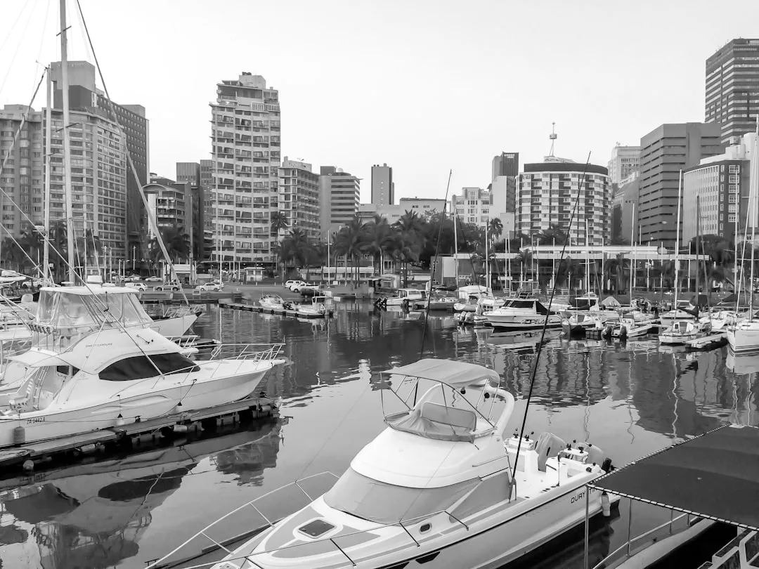 A marina with several docked boats in the foreground, tall modern buildings and palm trees in the background—an ideal waterfront setting for prime real estate.